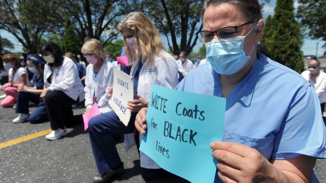 Dr. Lisa Sotir, Framingham Union Hospital emergency department chair, right, joined dozens of MetroWest Medical Center employees for a "White Coats for Black Lives" demonstration Friday in response to the recent events in Minneapolis.  The group kneeled for 8 minutes and 46 seconds, the time George Floyd spent struggling to breathe before he died with a police officer's knee on his neck.