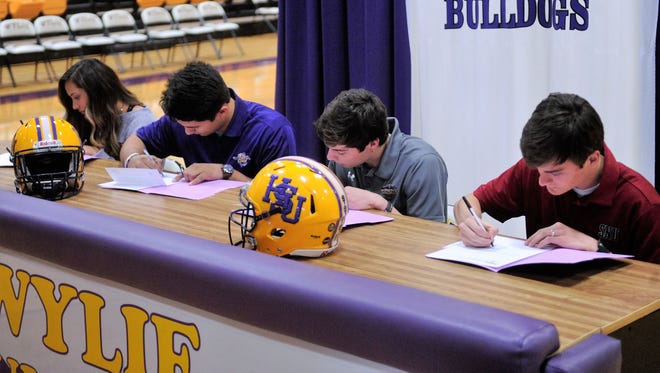 Wylie's (from left) Randie Dennison, Anthony Guerrero, Gatlin Martin and Preston Williams sign to play in college during the Signing Day ceremony at Bulldog Gym on Wednesday, Feb. 7. 2018.