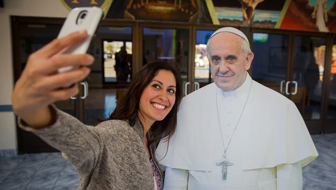 Desarae Diaz takes a selfie with a cardboard cutout of Pope Francis in the foyer of Holy Cross Catholic Church. According to youth minister Craig Bullock everyone who comes into the foyer has taken a photo of the cutout.