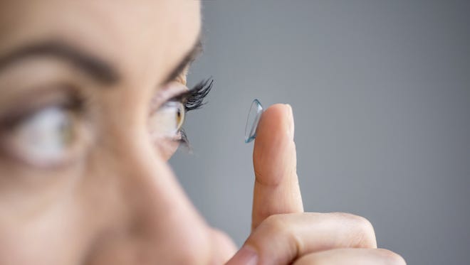 Woman inserting contact lenses.