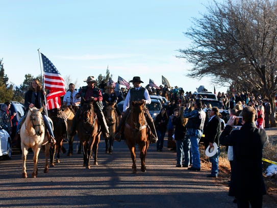 People line the road as a horse honor guard escorts