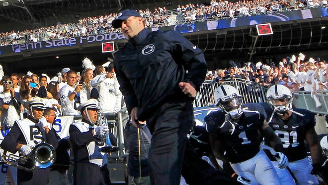 Penn State coach Bill O'Brien, center, leads his team onto the field at Beaver Stadium before a game against Central Florida in September. The NCAA said on Tuesday it will restore some of the scholarships it revoked from the school last year in the wake of the Jerry Sandusky child sex abuse scandal.