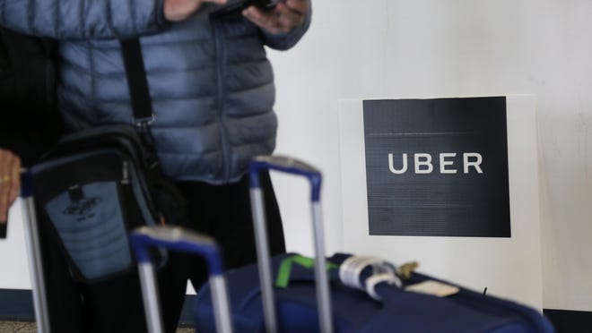 FILE - In this Wednesday, March 15, 2017, file photo, a traveler tries to book a ride with Uber at LaGuardia Airport in New York. Through a string of almost weekly scandals, Uber has managed to continue growing and hold onto the title of the world's largest ride-hailing service. In the latest misbehavior, hackers were able to steal data for 57 million riders and drivers, and Uber concealed it for a year. Riders and business experts say that hits people directly, and they won't be happy about it. (AP Photo/Seth Wenig, File)