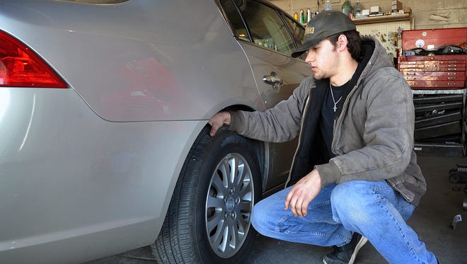 Hayden Hoffman of DeArmond's Service Center checks the condition of a car's tires during a vehicle inspection.