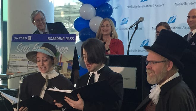 Nashville Mayor Megan Barry and Metro Nashville Airport Airport Authority CEO Rob Wigington applaud as Victorian carolers announce a new nonstop flight between Nashville and San Francisco.
