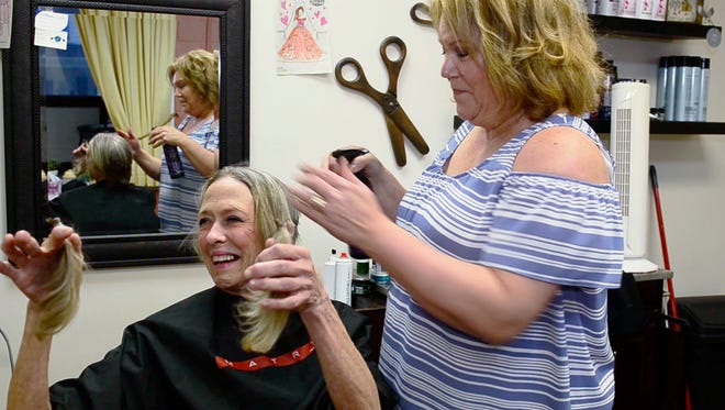 Patti Tucker holds up a lock of hair clipped by her friend Sandy Lagrou, manager of Friends Salon & Spa. Tucker will donate the hair to be used to make a child's wig. "