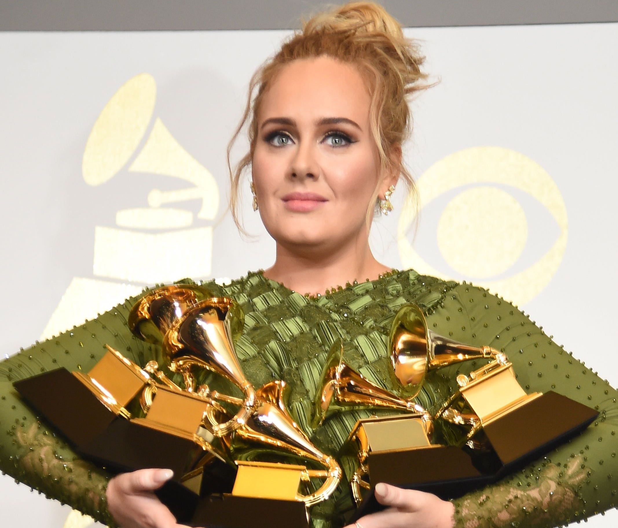 Adele poses in the press room with her trophies, including the top two Grammys of Album and Record of the Year for her blockbuster hit 