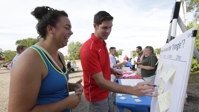 Jenna Moran, of Wisconsin Rapids, laughs with Mayor Zach Vruwink while writing down suggestions about downtown improvements on a board at the Wisconsin Rapids Block Party August 23, 2016.