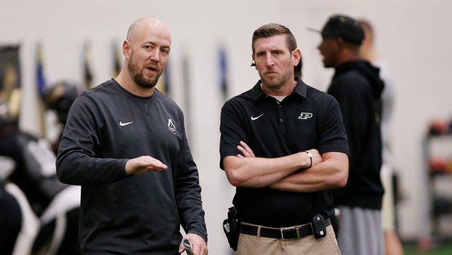 Justin Lovett, left, director of football strength and conditioning, talks with Ryan Collins, associate director of sports medicine, as they watch players during Purdue spring football practice Friday, March 30, 2018, inside the Mollenkopf Athletic Center.