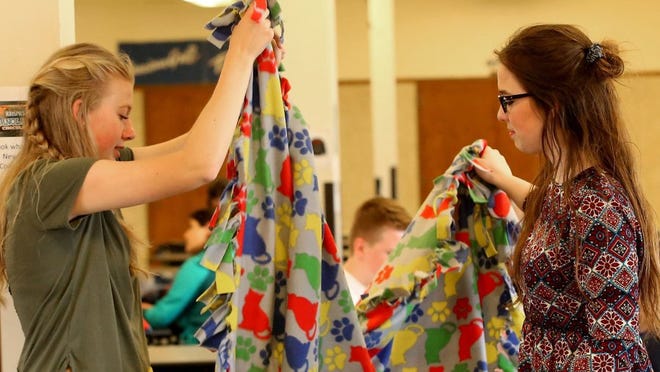 Central Kitsap High School students Courtney Murray, 17, (left) and Caitlyn McConnell, 16, fold a finished blanket as they and fellow students create fleece blankets for Project Linus on Wednesday.