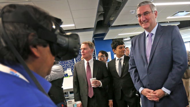 Gov. Eric Holcomb, right, smiles as Daniel Colon, left, demonstrates a virtual reality device for designing a home, during a tour at the ribbon cutting event for the Infosys tech and innovation hub, Tuesday, Mar. 6, 2018.