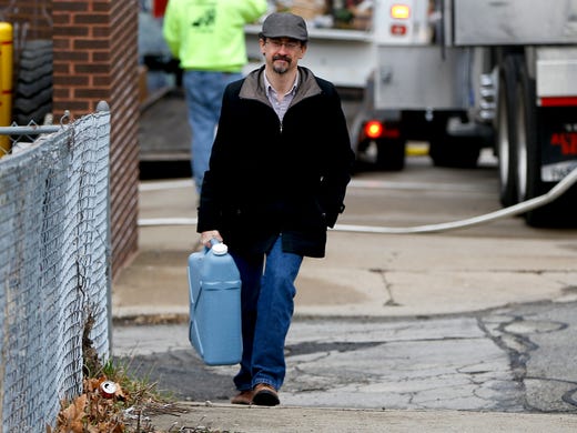 Tim Stuhldeher carries a container of water to his