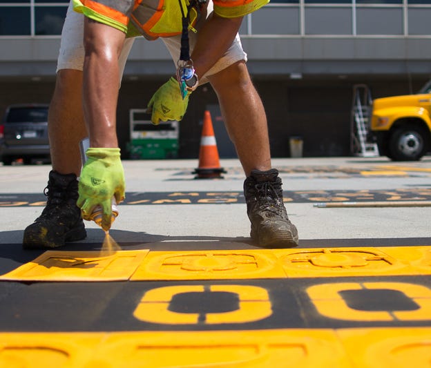 Hector Murcia spray paints aircraft names onto the parking locations on a terminal A ramp at Washington Dulles International Airport on June 29, 2018.