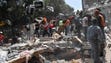 People remove debris of a collapsed building looking