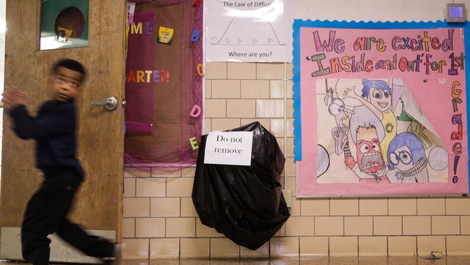 In this photo taken in early February, a student walks past a drinking fountain covered in a bag to stop students from drinking due to the Flint water crisis during the school day at Northridge Academy charter school in Flint.