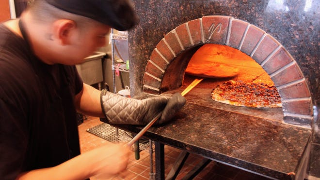 In this Sept. 5, 2014 photo, a cook prepares pizza at Coalfire pizzeria in Chicago. Chicago is one of a handful of cities across the country, like Boston, Milwaukee and New York, with companies that offer tours of the local pizza scene.