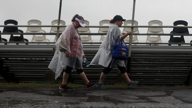 Race fans walk in the rain before the NASCAR Sprint Cup Series Pennsylvania 400 at Pocono Raceway on July 31, 2016.