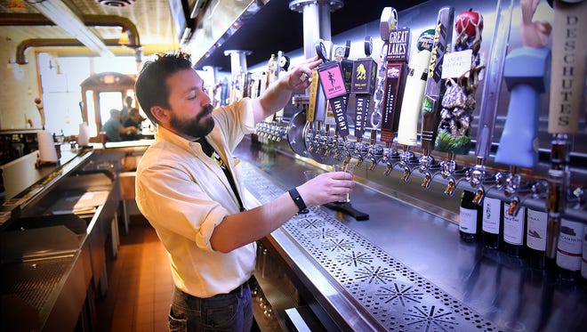 7 West Taphouse general manager Adam Hainlin pours from one of 50 available taps Wednesday at the business in St. Cloud.