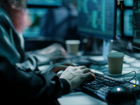 Close-up Shot of Hacker using Keyboard. There is Coffee Cups and Computer Monitors with Various Information.