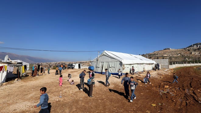 Syrian refugee children walk outside a tent being used as a school at a Syrian refugees camp in the village of Baaloul, Lebanon, in the west of the Bekaa Valley on December 16, 2014.