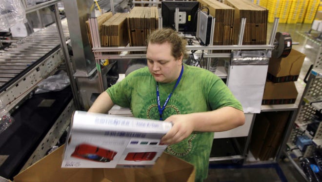 Joshua Lukens, a packer at Amazon’s fulfillment center in Hebron, packs merchandise for shipment. Amazon has four area facilities.