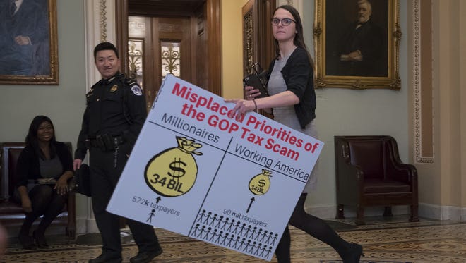 A Democratic aide walks past the Senate chamber on Dec. 1 with a chart to be used in the debate against the Republican tax bill.