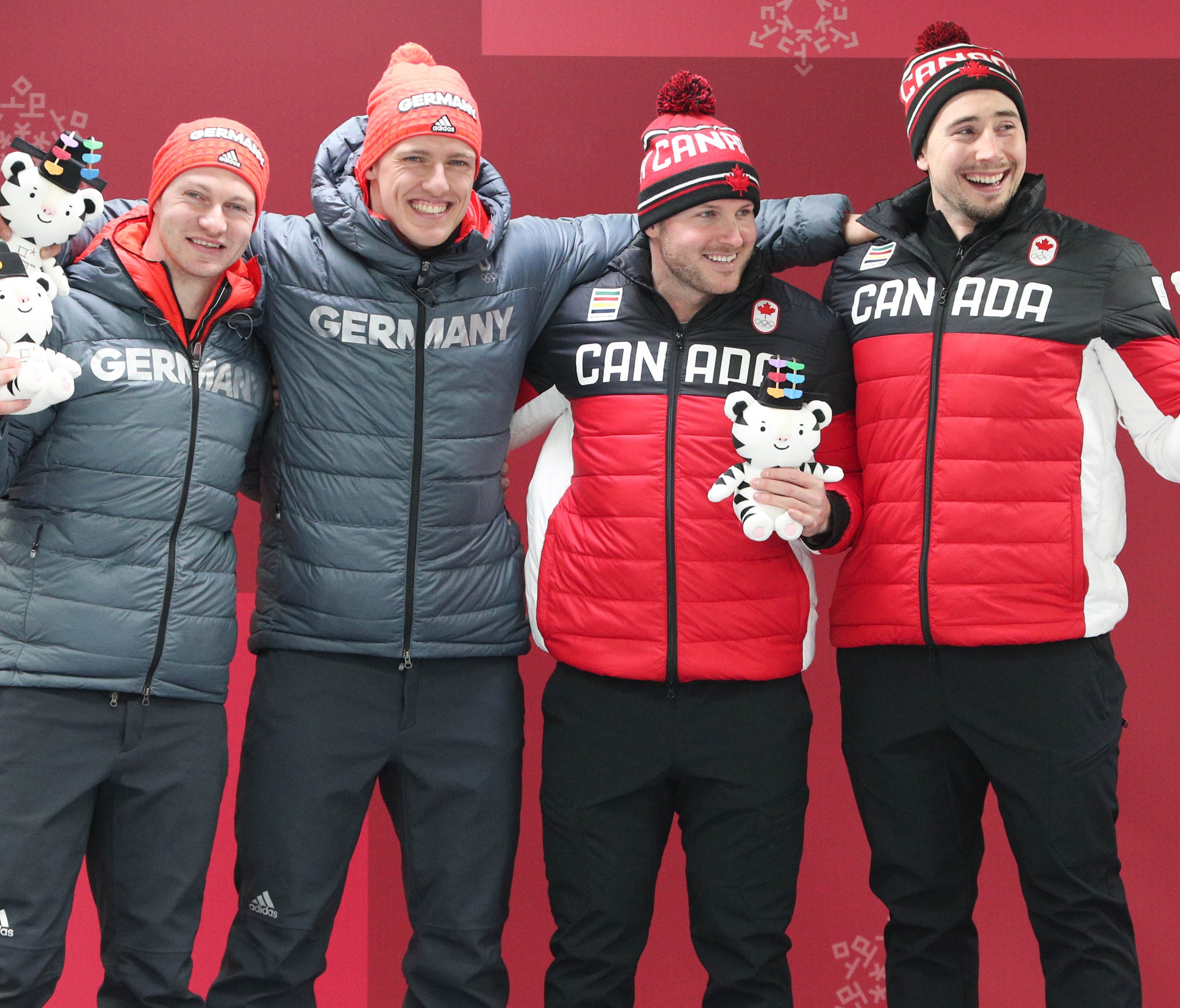 Justin Kripps and Alexander Kopacz of Canada and Francesco Friedrich and Thorsten Margis of Germany celebrate a tie for gold in the two-man bobsled.
