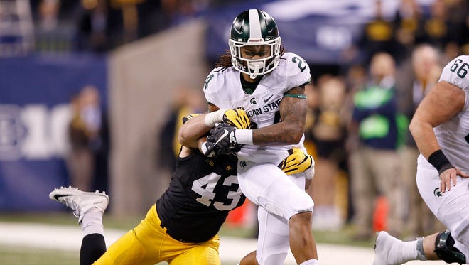 Gerald Holmes #24 of the Michigan State Spartans is dragged down by Josey Jewell #43 of the Iowa Hawkeyes in the Big Ten Championship at Lucas Oil Stadium on December 5, 2015 in Indianapolis, Indiana. 
