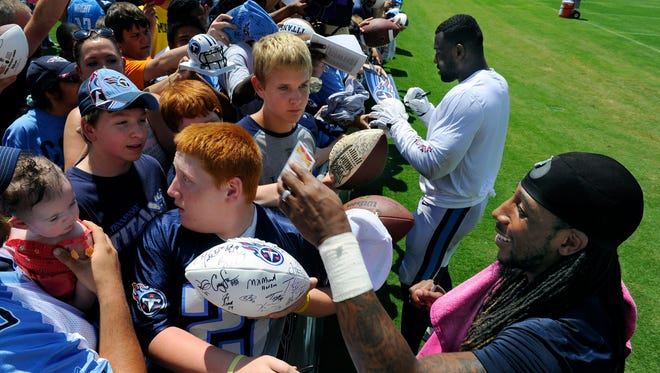 Titans tight end Delanie Walker (lt) and running back Dexter McCluster sign autographs for fans following the first day of training camp at St. Thomas Sports Park Saturday July 26, 2014, in Nashville, Tenn.