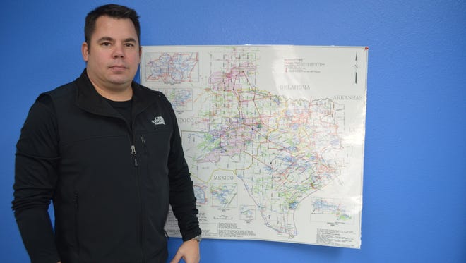 Matt Carter pictured in the office of Carter Wind Energy. Behind him is a map of the power transmission lines that crisscross the state.