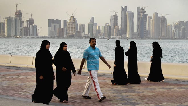 Qataris walk by the sea in Doha, Qatar.