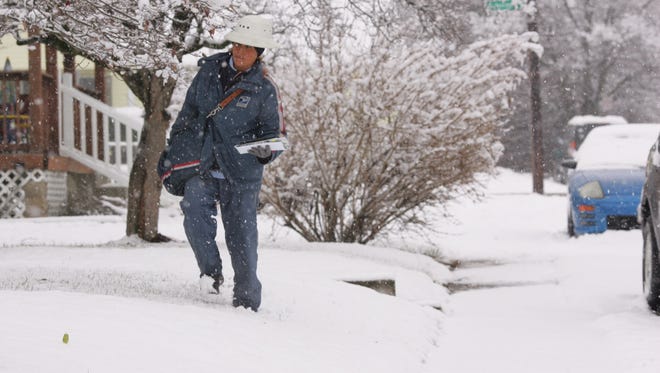 Alice Thorne carries mail Monday morning through the snow on Philmont Avenue.