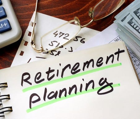 Notebook with retirement planning written on front, along with calculator, spreadsheet, and stack of money on a desk.