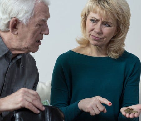 A confused elderly man staring at coins being held and pointed at by a woman next to him.