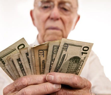 An elderly man counting cash in his hands.