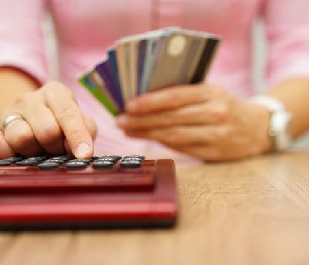 Woman holding credit cards while using a calculator