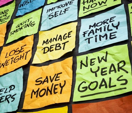 colorful sticky notes on a blackboard with goals on each such as save money manage debt more family time