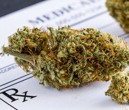 A cannabis bud lying atop a doctor's prescription pad.