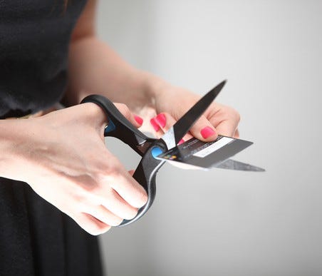 Person cutting up a credit card with scissors.