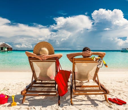 man and woman relaxing in lounge chairs on a beach in the Maldives