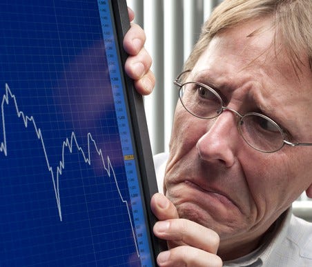 A worried investor looking at a plunging stock chart on his computer screen.
