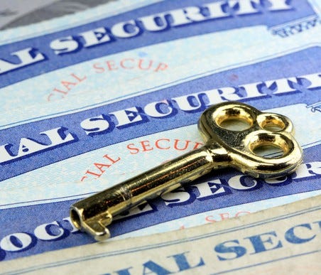 Three Social Security cards under a brass key.
