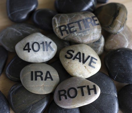 Smooth stones with words written on them such as retire, 401k, IRA, Save, and Roth.