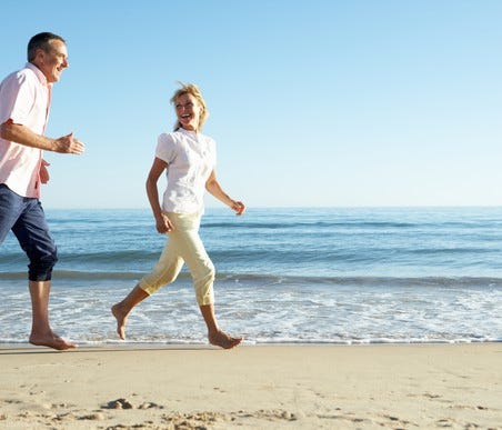 Mid-aged couple running along the beach
