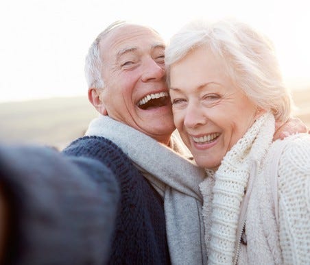 Senior couple laughing while taking a selfie at the beach