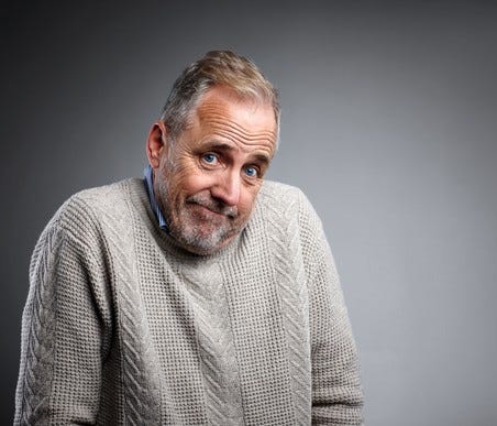 A mature man shrugging his shoulders.