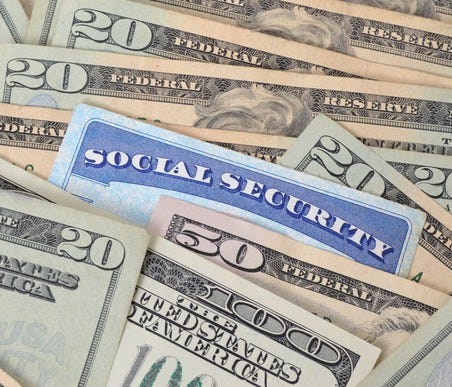 Social Security card inserted in a pile of money.