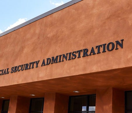 Brown stucco building with Social Security Administration on the side above glass doors.