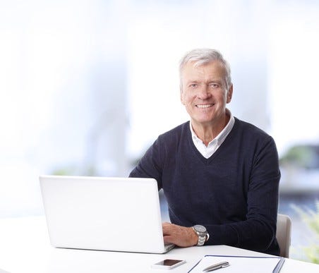 Smiling older man at a laptop.