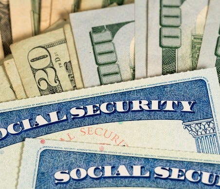 Social Security cards lying atop fanned piles of cash bills.
